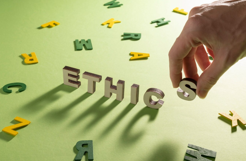Costruzione della parola 'ethics' con lettere in legno su sfondo verde, concetto di etica e responsabilità organizzativa.