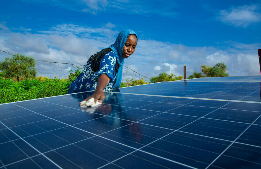 Donna che pulisce pannelli solari in Mauritania, simbolo dell’inclusione femminile nella transizione energetica e nell’azione climatica