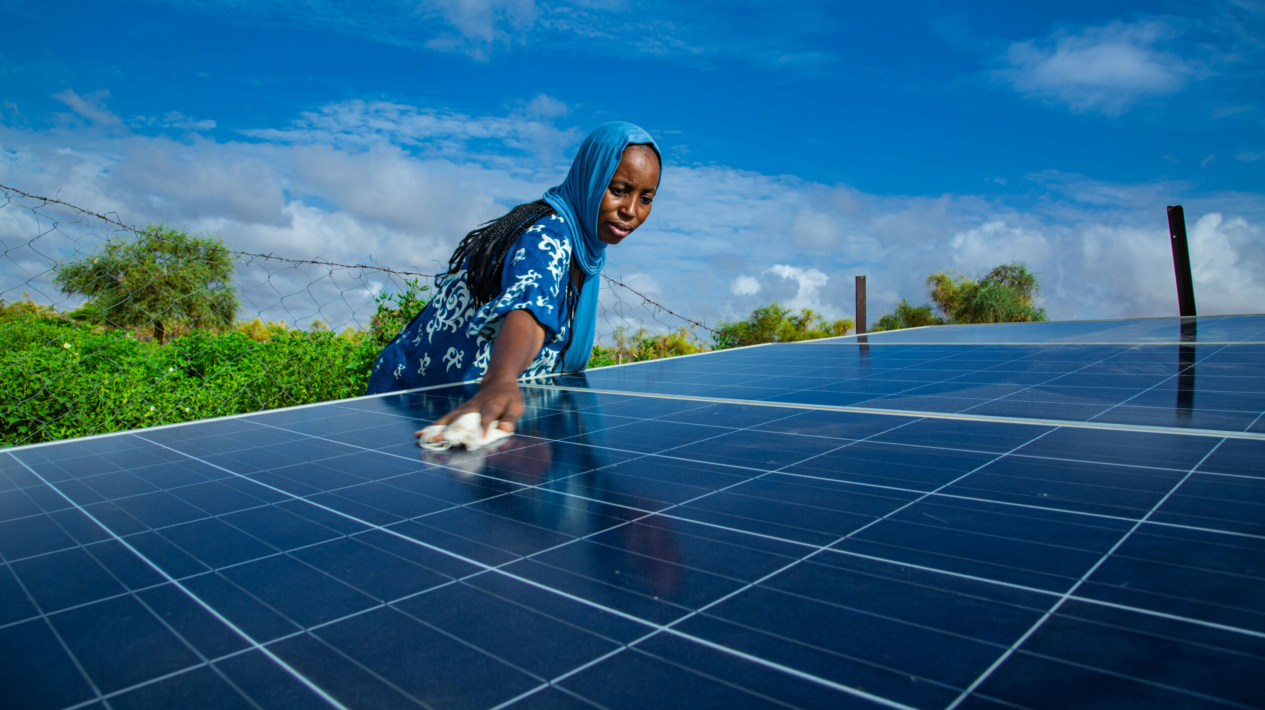 Donna che pulisce pannelli solari in Mauritania, simbolo dell’inclusione femminile nella transizione energetica e nell’azione climatica