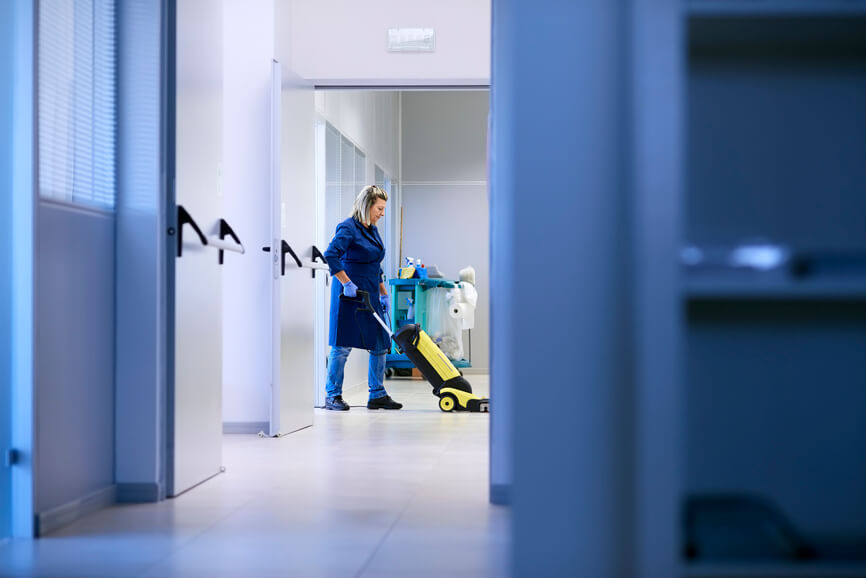 Donna che passa l'aspirapolvere in un'azienda.